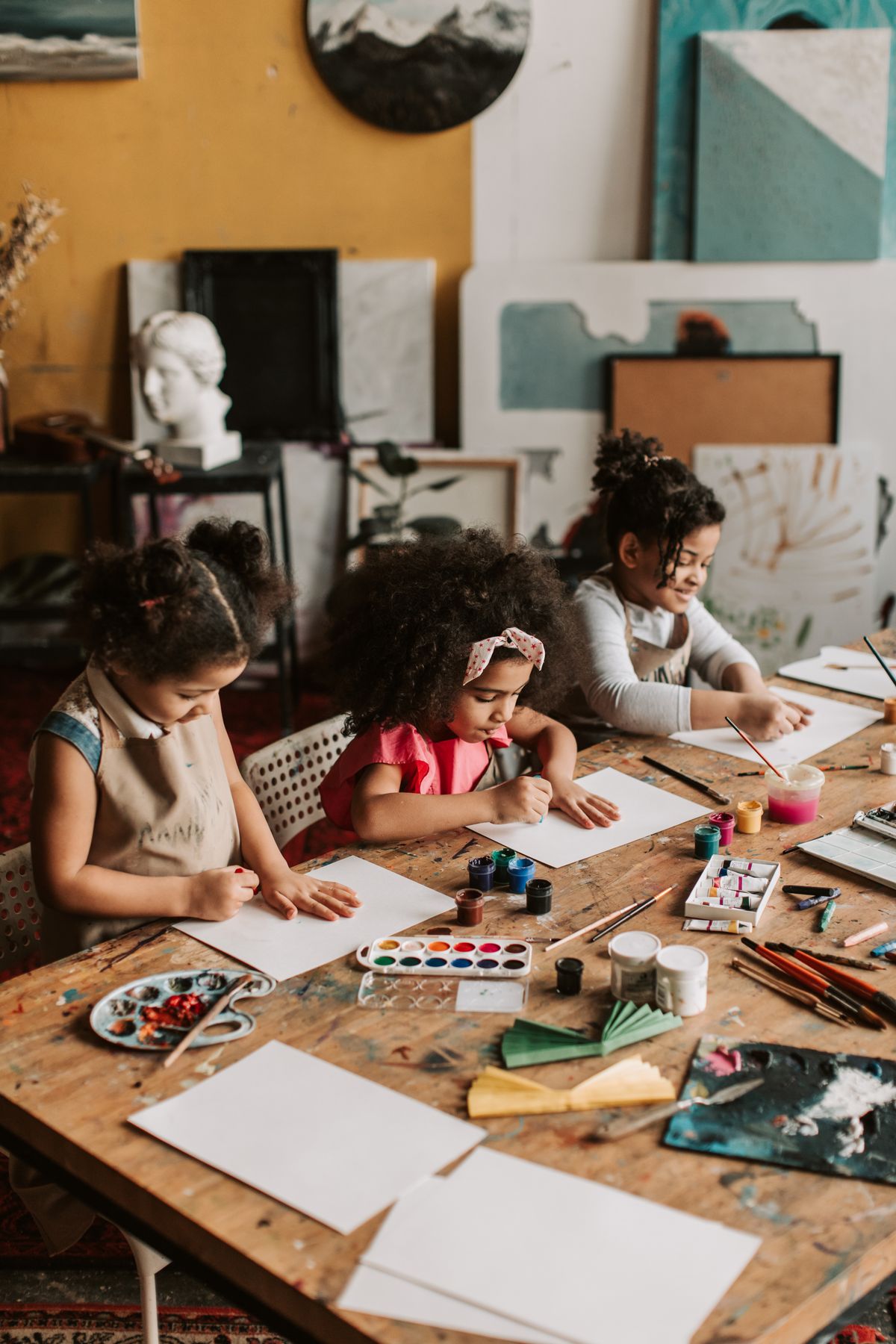 Children painting with watercolours at a table during a family art class